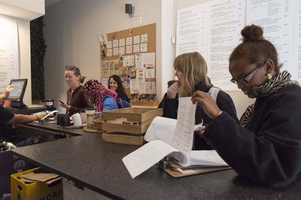 Students and adults reviewing paperwork in cafe