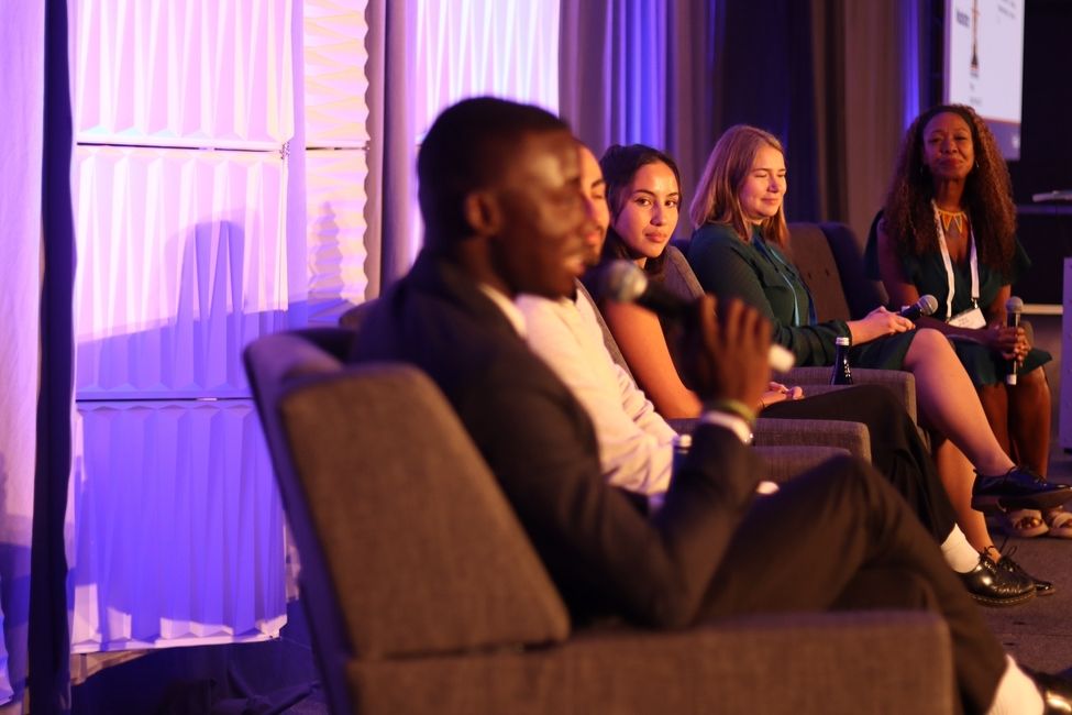 A row of panelists sit on a stage waiting to be asked a question