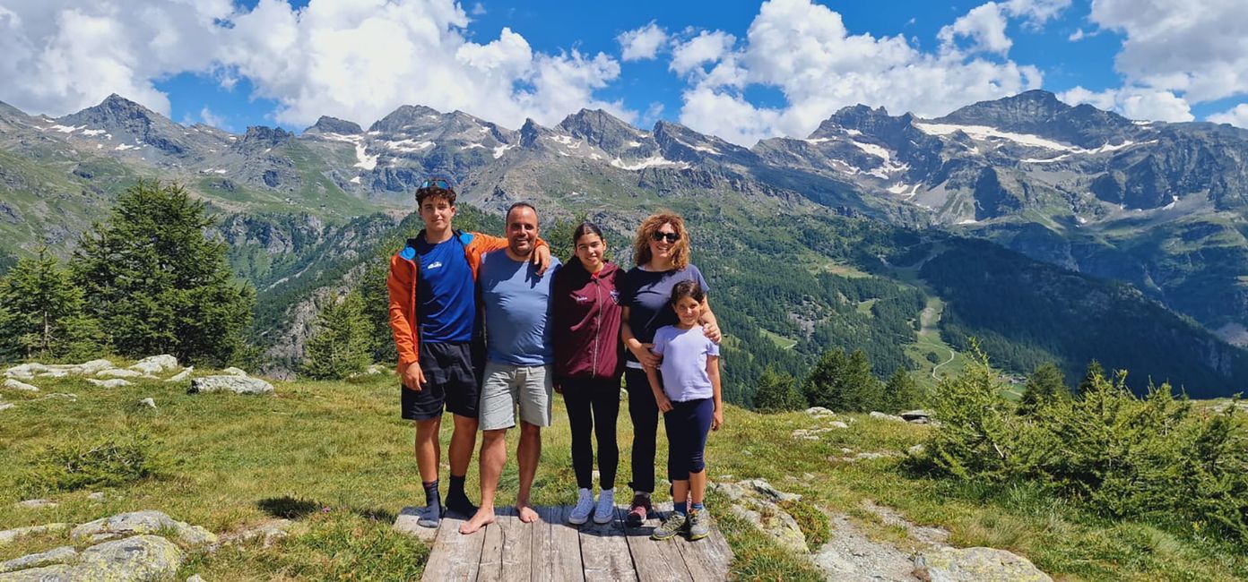 Homestay family with student participant posing in front of scenic mountains