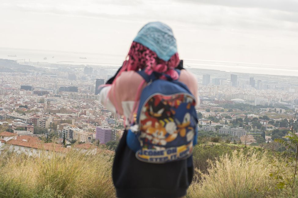 Student taking photo on hill above city while hiking