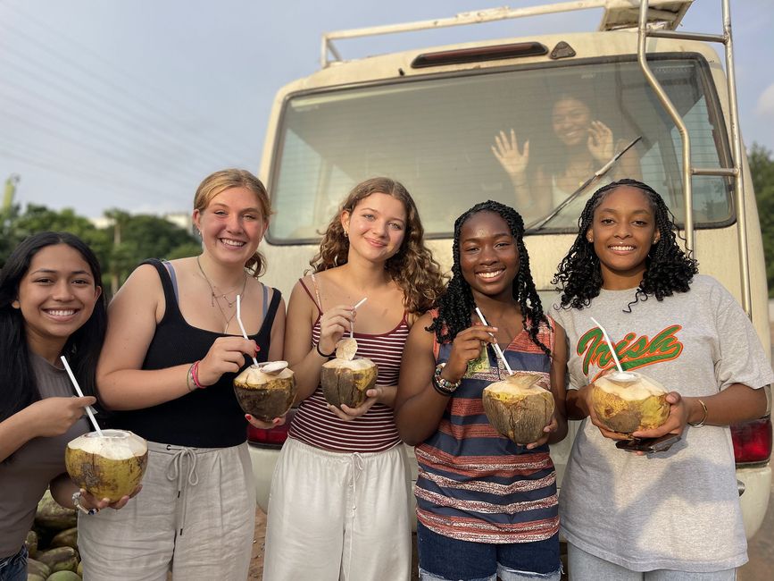 students posing with coconuts in front of a truck in Legon