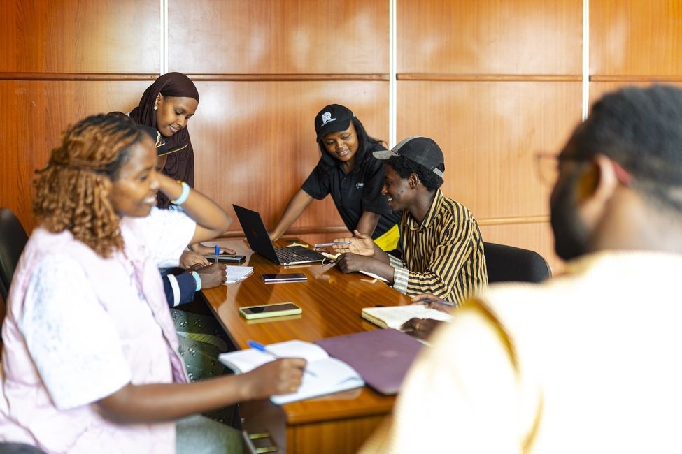 students standing around a laptop smiling