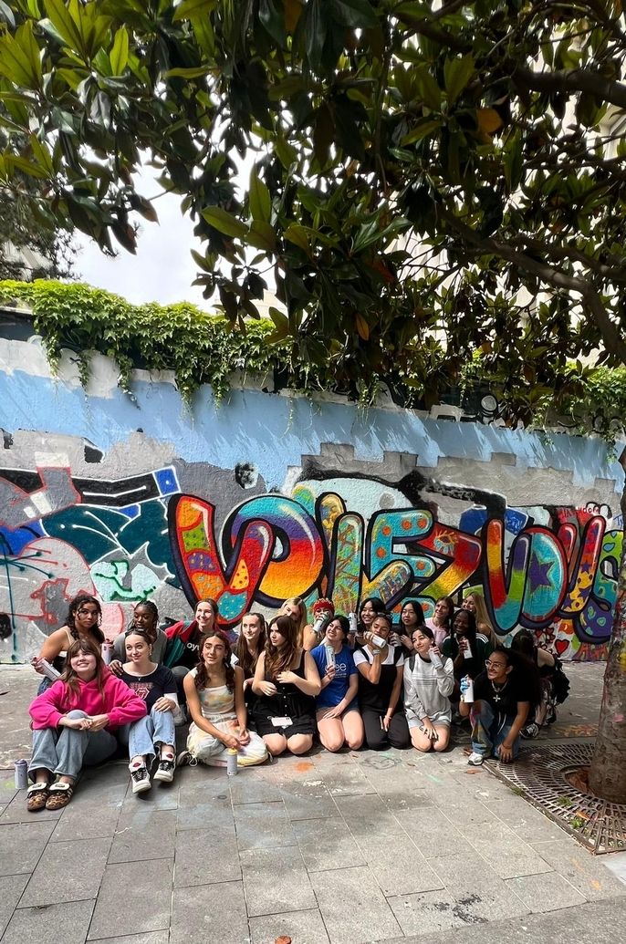 HSSA students pose in front of their graffiti mural which spells out Voulez-Vous. The chosen phrase is a reference to the song "Voulez-Vous", written by ABBA and featured in Mama Mia. 