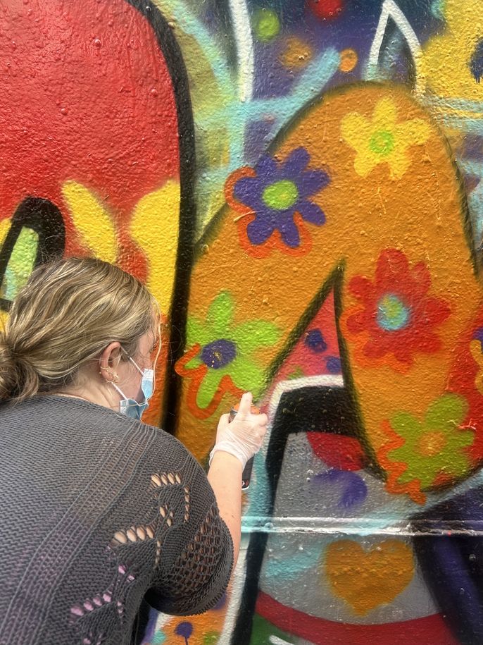HSSA student Katie Janak sprays flowers on the graffiti mural