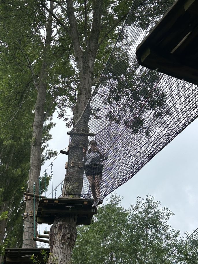 Fashion and Design student Brooke Neigler crosses a net obstacle in the trees