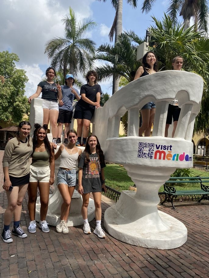 A group of students gather to take a picture in the iconic chairs.