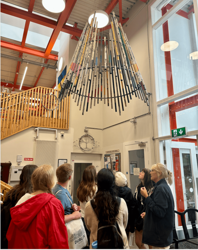 Students looking at a light fixture made from used poles 