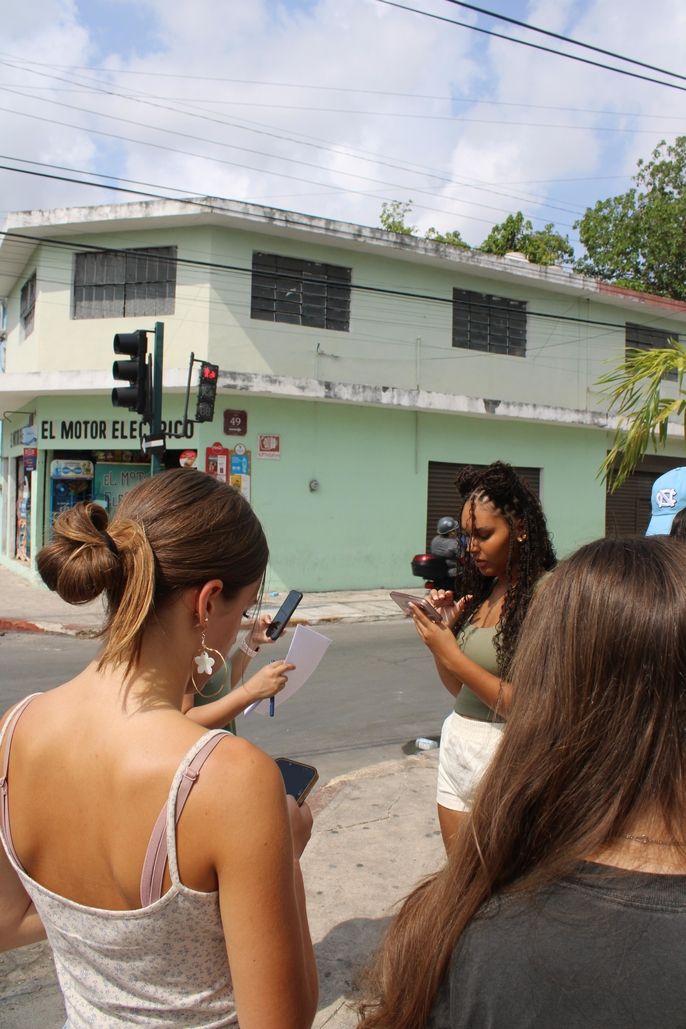 A group of students are helping each other navigate in the streets of Merida.