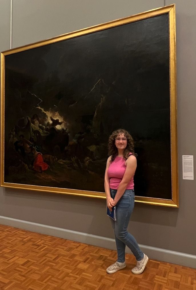 One female student with glasses standing in front of her favorite work of art