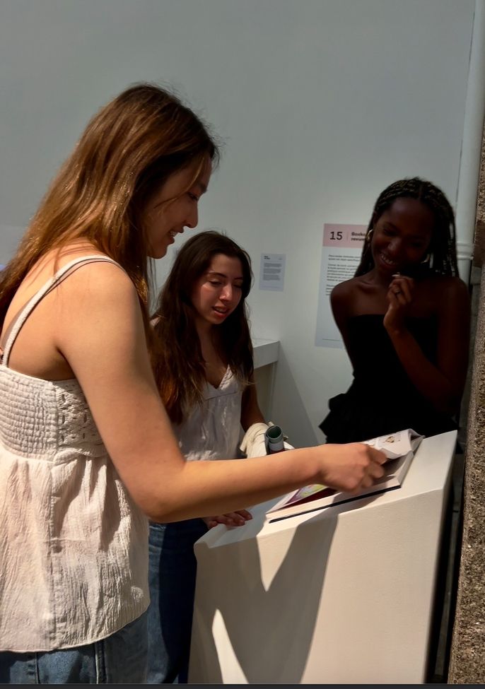 Three female students looking at art