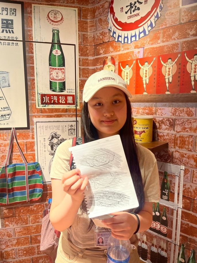 Student holding up a paper with impressed stamps from an interactive and colorful exhibit
