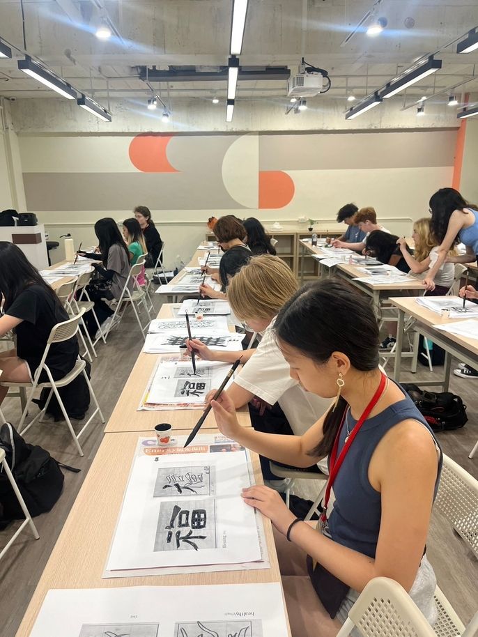 Two students practicing calligraphy on paper
