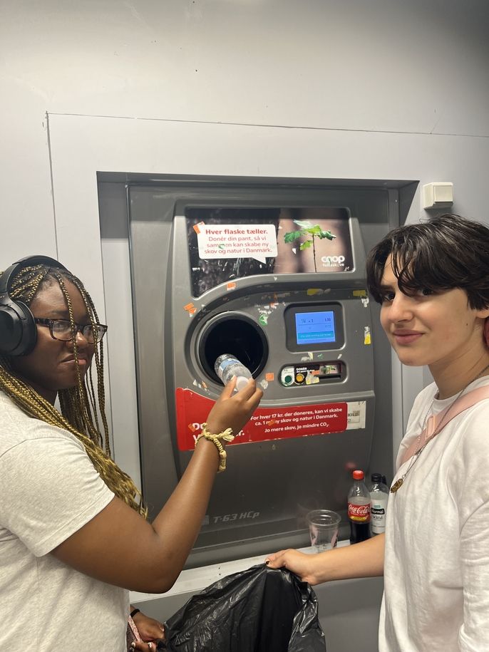 Two students using a recycling machine at a grocery store to receive "pant" money back.