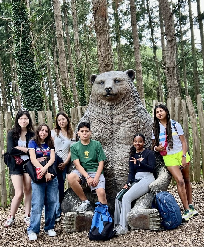 Students sitting in front of Bear sculpture 