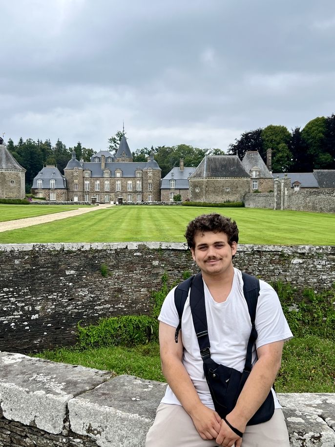 Male teen sitting in front of chateau
