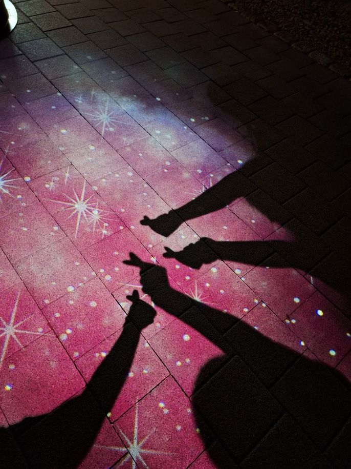 a picture in one of the light shows leading up to the wine cave, featuring my friends and i doing finger hearts <3