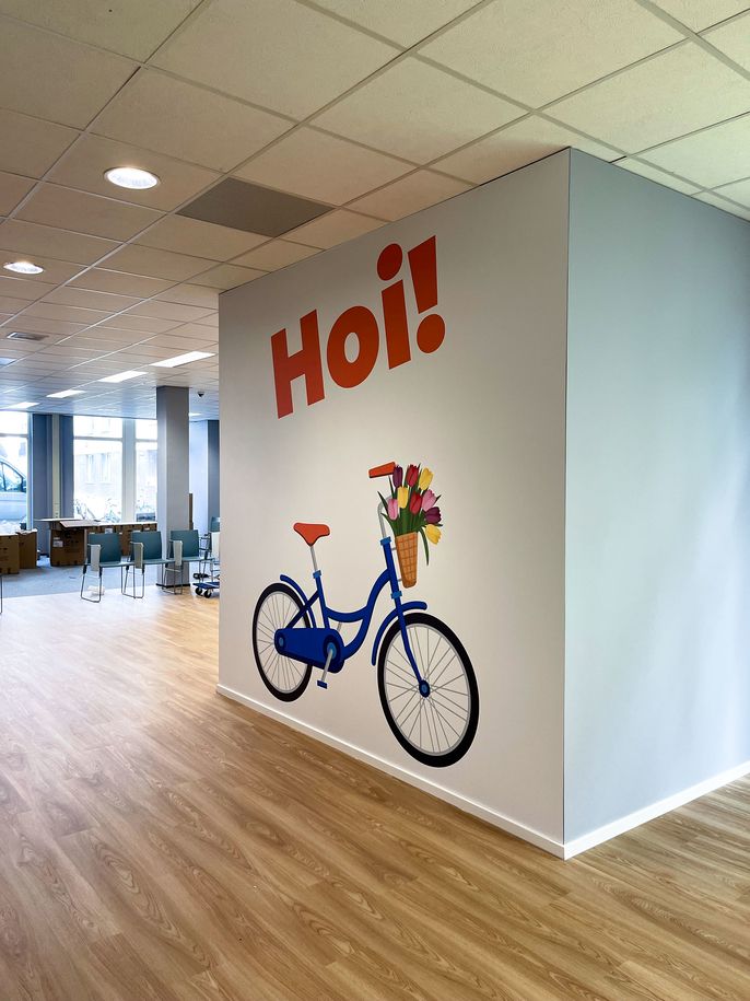 artwork in the ciee amsterdam center for a bicycle with a basket attached to handlebars and the word "hoi!" above it