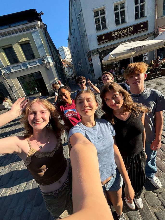 Group selfie high schoolers standing on cobbled street in Europe