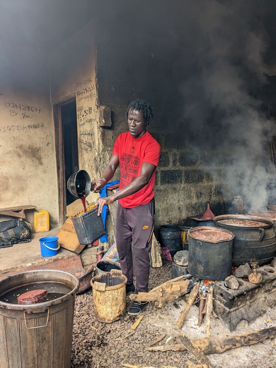 Kojo Adom, a native of the Ntonso Adinkra village pours dye that has been generated from boiling tree bark into a container. When the dye is boiled again, it turns darker.