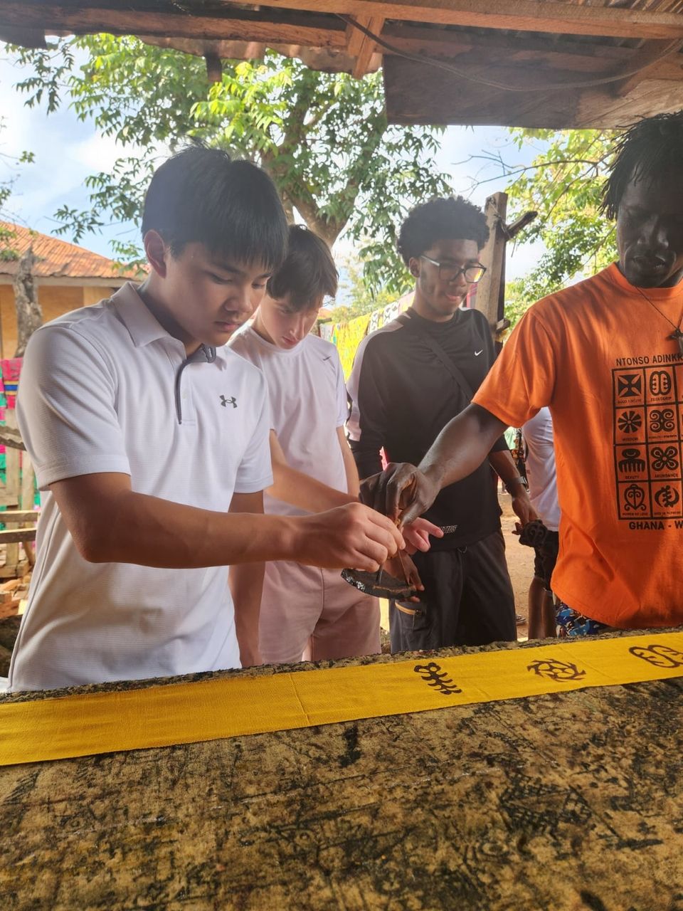 Nicholai Lee, one of the students on the 2024 HSSA program, hand-stamps a strip of woven fabric.s